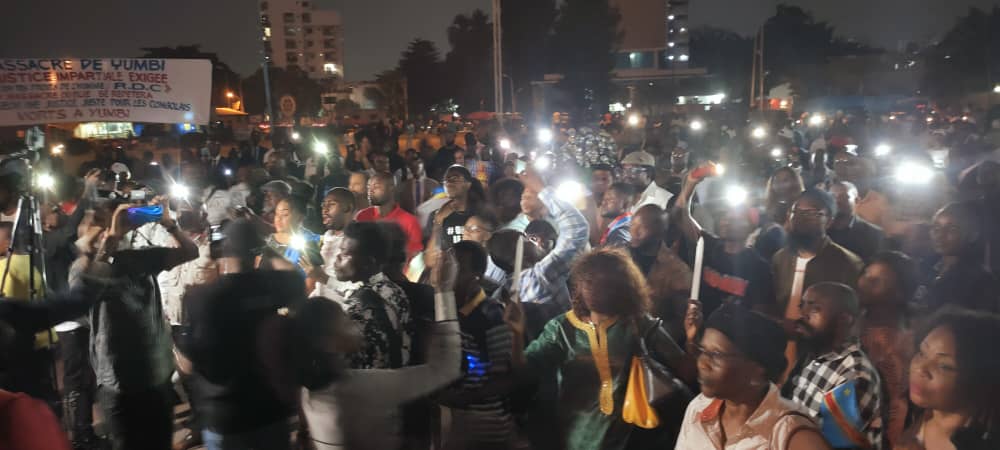 crowd of people gathered at night at the place du Genocost in Kinshasa